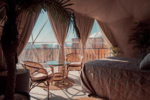 Habitación con cama, sillas y mesa de cristal. en O'MIR glamping эко-отель Актау en Kyzylkum