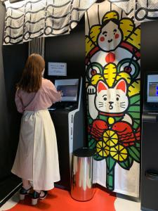 une femme debout devant une machine avec un chat dessus dans l'établissement HOTEL TAVINOS Kyoto, à Kyoto