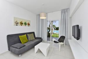 a living room with a couch and a tv at Mon Repos Hotel in Ayia Napa