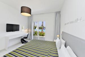 a white bedroom with a bed and a tv at Mon Repos Hotel in Ayia Napa