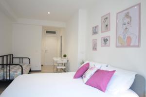 Un dormitorio con una cama blanca con almohadas rosas y moradas en Republic B&B, en Bitonto