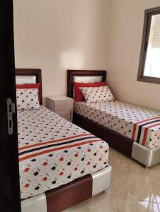 duas camas num pequeno quarto com em Appartement Cozy Louizia em Ben Yakhlef