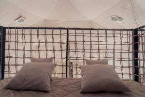 uma cama com duas almofadas numa tenda em O'MIR glamping эко-отель Актау em Kyzylkum