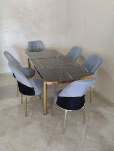 una mesa de madera con 4 sillas alrededor en Appartement Cozy Louizia en Ben Yakhlef