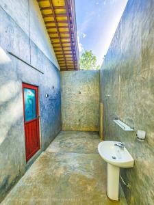 a bathroom with a sink and a red door at Green Village Safari Resort in Udawalawe