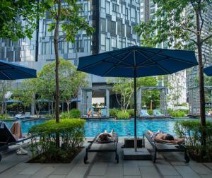 personas tumbadas en sillas en una piscina con sombrilla en AXQUISITE SUITES at KLCC, en Kuala Lumpur