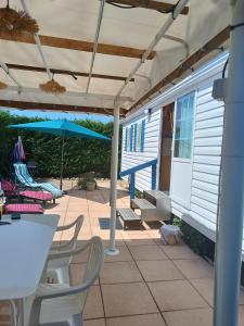 eine Terrasse mit einem Tisch, Stühlen und einem Sonnenschirm in der Unterkunft Mobil home 6 personnes climatisation Sainte Croix du Verdon - Gorges du Verdon in Sainte-Croix-de-Verdon