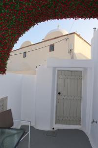 a white house with a white door and red flowers at Lamar Cave house in Emporio Santorini