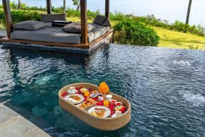 una cesta de comida en el agua junto a una piscina en AYANA Villas Bali, en Jimbaran