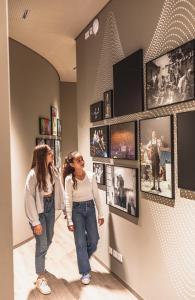 Due donne guardano le foto su un muro di Jugendherberge München City a Monaco