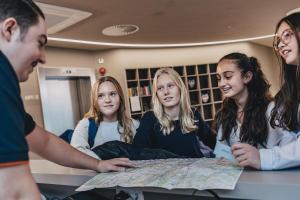 a group of people sitting around a table looking at a map at Jugendherberge München City in Munich +24 photos