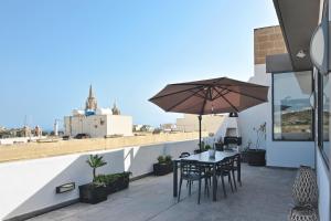 a patio with a table and chairs and an umbrella at Millennium Penthouse with private Hot Tub Gozo in Għajnsielem