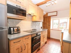 uma cozinha com armários de madeira e um aparelho de aço inoxidável em Primrose Cottage em Wells-next-the-Sea