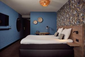 ein Schlafzimmer mit einem großen Bett mit blauer Wand in der Unterkunft Van der Valk Texel - De Koog in De Koog