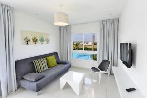 a living room with a couch and a table and a tv at Mon Repos Hotel in Ayia Napa