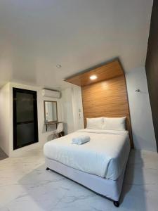 a bedroom with a large white bed with a wooden headboard at Mbs Hotel (Maramag Business Suites) 