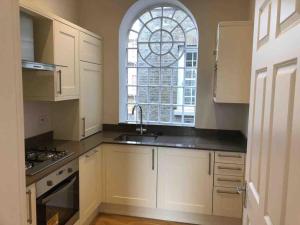 a white kitchen with a sink and a window at Victorian Apartment in London