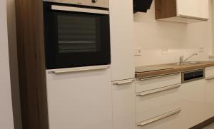 eine Küche mit weißen Schränken und einer Mikrowelle in der Unterkunft Dinaro Suite, Sauna & Garden in Franzensfeste