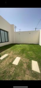 a large yard with a white wall and grass at شاليه الجوري in Ilbaras