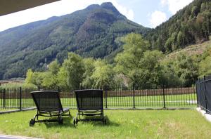 zwei Stühle im Gras vor einem Berg in der Unterkunft Dinaro Suite, Sauna & Garden in Franzensfeste