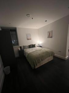 a bedroom with a bed and a lamp on a table at Spacious Sleep 8 Flat 20 mins Central London BP9 in London