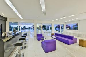 a lobby with purple couches and tables and windows at Mon Repos Hotel in Ayia Napa
