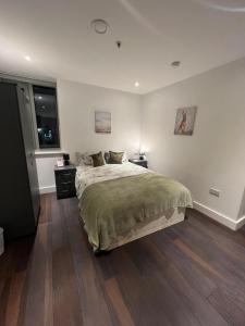 ein Schlafzimmer mit einem großen Bett und Holzboden in der Unterkunft Spacious Sleep 8 Flat 20 mins Central London BP9 in London