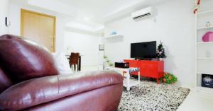 Cozy & Elegant The Mansion Jasmine Tower Capilano في جاكرتا: غرفة معيشة مع أريكة جلدية وتلفزيون