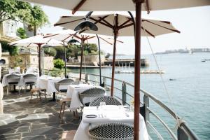 a row of tables and chairs with umbrellas and the water at Castelbrac Hotel & Spa in Dinard