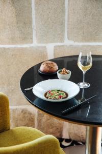 a table with a plate of food and a glass of wine at Castelbrac Hotel & Spa in Dinard