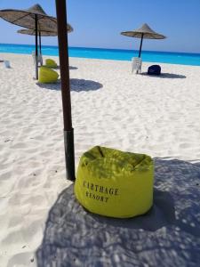 un contenitore giallo seduto su una spiaggia con ombrelloni di شاليه قرية قرطاج الساحل الشمالي a El Alamein