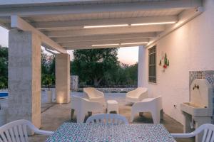a patio with white chairs and a table and a table and chairs at Villa Antonietta in Carovigno