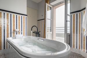 a large bath tub in a bathroom with a window at Castelbrac Hotel & Spa in Dinard