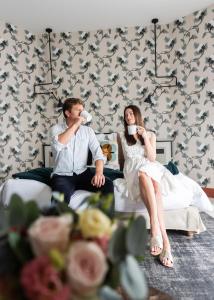 a man and a woman sitting on a bed drinking coffee at Castelbrac Hotel & Spa in Dinard