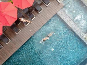 a person swimming in a pool with an umbrella at SKYVIEW Hotel Bangkok - Sukhumvit in Bangkok