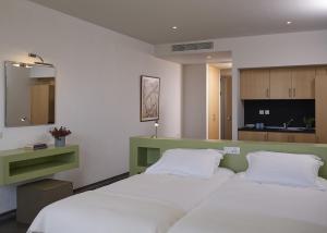 a bedroom with a large white bed and a kitchen at Leivatho Hotel in Svoronata