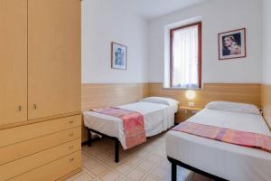 a bedroom with two beds and a dresser and a window at Appartamenti Gianni in Torri del Benaco