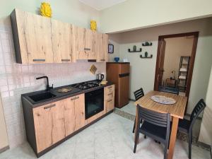 una cucina con armadi in legno, tavolo e piano cottura di Casa Calilla - 30m dal mare a Lampedusa