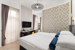a bedroom with two beds and a desk and a television at Maison Bistro & Hotel in Budapest