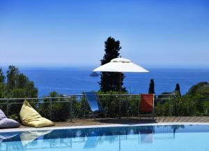 a swimming pool with an umbrella and some chairs at Leivatho Hotel in Svoronata