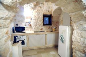 uma cozinha com um frigorífico branco e uma parede de pedra em Casa Vacanze - Al Ma Chlo' em Fasano