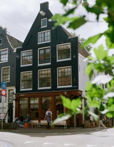 een zwart gebouw waar mensen buiten zitten bij hotel calisto in Amsterdam