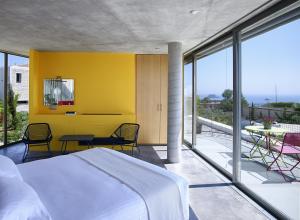 a bedroom with a yellow wall and a table and chairs at Leivatho Hotel in Svoronata