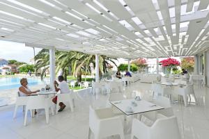 a restaurant with white tables and white chairs at Mon Repos Hotel in Ayia Napa