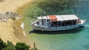a boat on the water next to a beach at Lovely Santorini Villa 3 Bedrooms Villa Petra Private Pool & Outdoor Dining Area Exo Gialos in Karterados