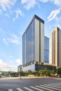 ein hohes Glasgebäude mit einer Straße davor in der Unterkunft Hilton Garden Inn Shenzhen Guangming in Shenzhen