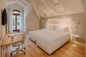 um quarto com uma grande cama branca e uma secretária em NH Collection Torino Santo Stefano em Turim