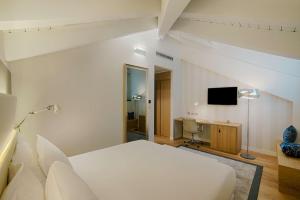 a bedroom with a bed and a desk and a television at NH Collection Torino Santo Stefano in Turin
