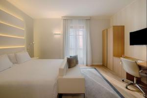 Cette chambre comprend un grand lit blanc et un bureau. dans l'établissement NH Collection Torino Santo Stefano, à Turin