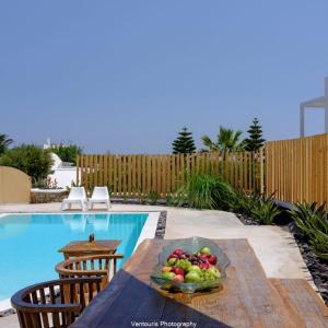 a bowl of fruit on a table next to a pool at Beautiful Santorini Villa 3 Bedrooms Villa Phos Private Pool and Lovely Sea View Exo Gialos in Karterados